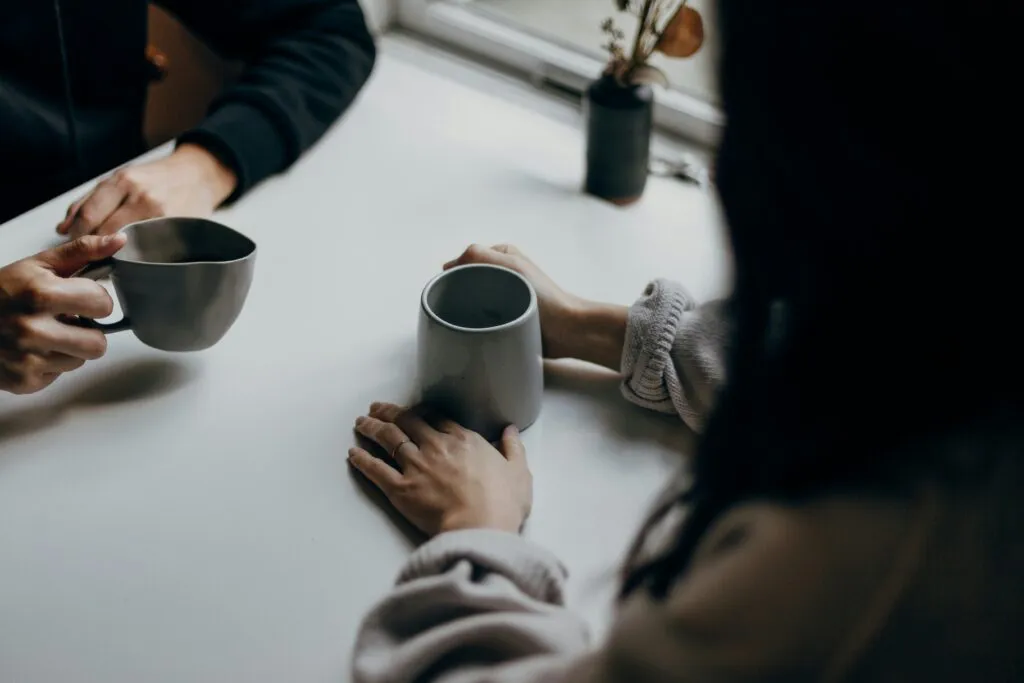 Two individuals drinking coffee from mugs